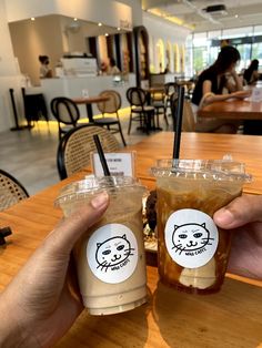 two people holding up cups with drinks in front of them on a table at a restaurant