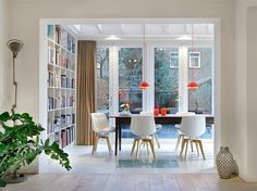 a dining room table with chairs and bookshelves in front of the glass doors