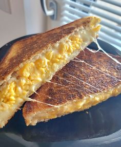 a grilled cheese and egg sandwich on a blue plate with a window in the background