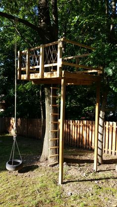 a swing set in the middle of a yard with a tree and fence behind it