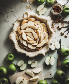 an apple pie with sliced apples in the middle and knifes on the table next to it