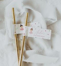 two gold straws are sitting next to each other on a white cloth covered surface