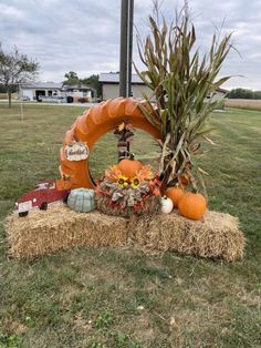 a hay bale filled with pumpkins and other fall decorations sitting on top of a grass covered field