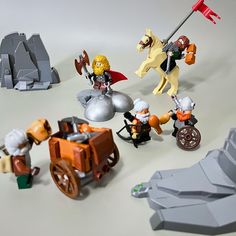 legos are arranged on a table with toys like horses, carriages, and people