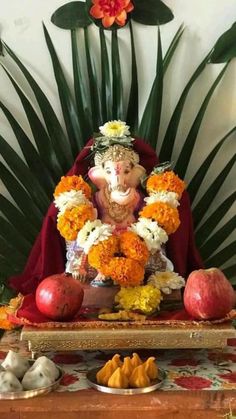 an elephant statue sitting on top of a wooden table next to fruit and vegetables in bowls