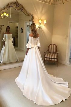 a woman in a white wedding dress looking at herself in the mirror with her reflection