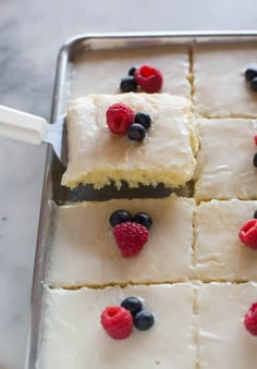 a pan filled with white frosting and raspberries on top of each other