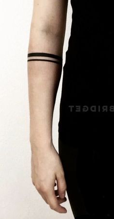 a woman wearing a black shirt and holding her arm with a wrist tattoo on it