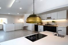 a large kitchen with white cabinets and gold pendant light hanging from it's ceiling