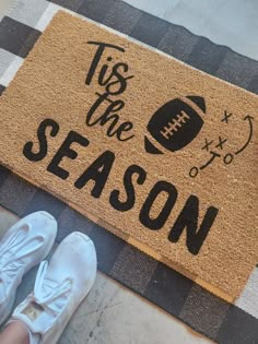 a person standing next to a door mat that says tis the season and football on it