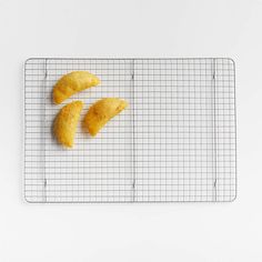 three pieces of food sitting on top of a wire rack next to a white wall