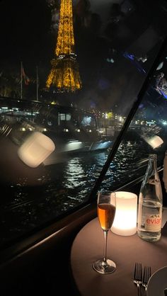 a table that has some wine on it and a bottle in front of the eiffel tower