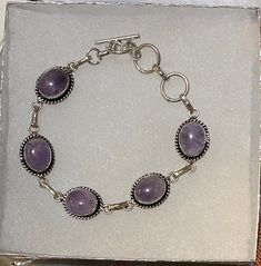 This eight inch artistically handcrafted Amethyst bracelet would be a perfect gift or addition to your own collection! Each Amethyst measures approximately 1/2 inch in full length! The metal is silver plated. An 8-inch Amethyst Gemstone Bracelet is a stunning accessory that can add elegance and sophistication to any outfit.  This bracelet features natural amethyst stones that have a rich purple hue and a smooth texture.  Amethyst is known as a stone of spirituality, intuition, and peace. It can help to calm the mind, enhance creativity, and promote emotional balance.  The bracelet is made of plated silver and has a hook-to-hook clasp.  A perfect gift for yourself or someone special. Amethyst Bracelet Beads, Amethyst Stones, Purple Bracelet, Hippie Bracelets, Rich Purple, Dope Jewelry, Amethyst Bracelet, Amethyst Beads, Shell Beads