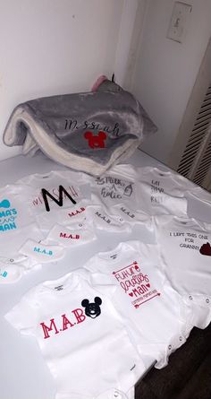 a pile of baby ones that are on top of a bed with mickey mouse t - shirts