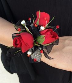 a red rose wrist corsage with black ribbon and white pearls on the end