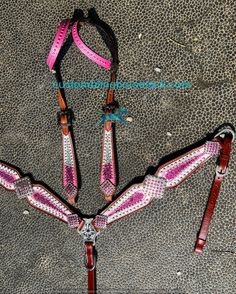 three pink and white horse bridles with matching reins on the ground next to each other