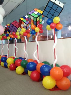 colorful balloons and streamers are lined up on the floor in front of a wall