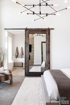 a bedroom with a bed, chair and mirror in it