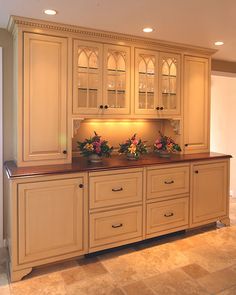 a kitchen with white cabinets and flowers on the counter