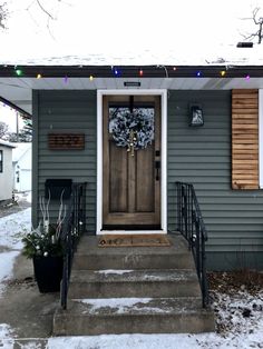 a gray house with christmas lights on the front door