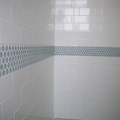 a bathroom with white tile and blue grouting on the shower wall is shown