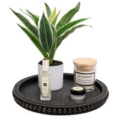 a potted plant sitting on top of a wooden tray next to a bottle of perfume