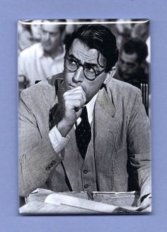 black and white photograph of a man in suit sitting at a desk with his hand on his chin