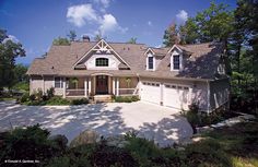 a large white house with two garages and lots of trees in front of it