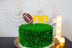 a football themed birthday cake with green grass on the top and one in the middle