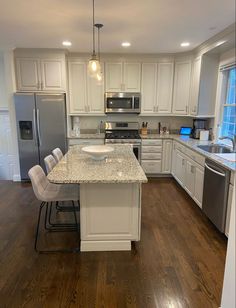 a kitchen with white cabinets and an island in the middle, surrounded by stainless steel appliances