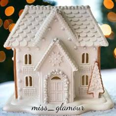 a white gingerbread house with trees and lights in the backgroung is miss glamour