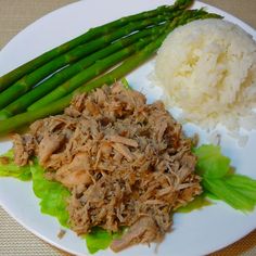 a white plate topped with rice and meat next to asparagus on top of lettuce