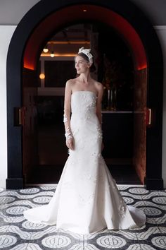 a woman in a white wedding dress standing on a tile floor next to an archway