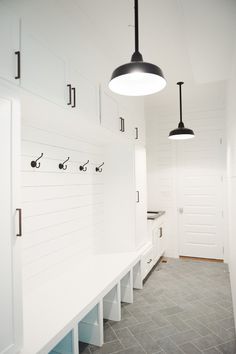 a kitchen with white cabinets and lights hanging from it's hooks on the wall