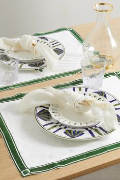 two plates with napkins on them sitting on a table next to a glass vase