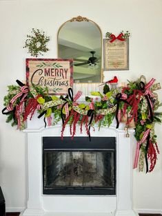 a fireplace decorated for christmas with red, green and white ribbons on the mantel