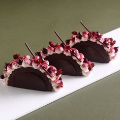 three pieces of chocolate covered with white and red toppings on a table next to each other