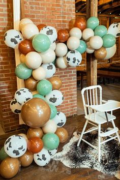 a chair sitting in front of a balloon arch with cow print balloons hanging from it