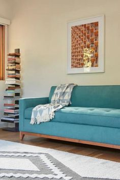 a blue couch sitting on top of a hard wood floor next to a white rug