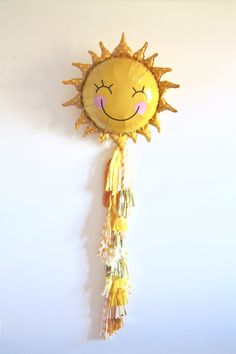 a yellow sun decoration hanging from the side of a wall next to a white wall