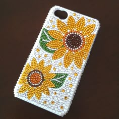 a phone case with sunflowers on it sitting on top of a wooden table