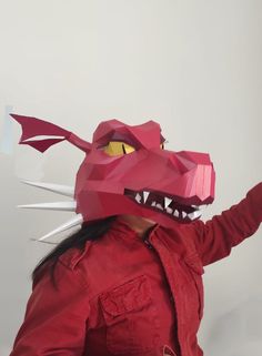 a woman in a red shirt is wearing a paper dragon mask