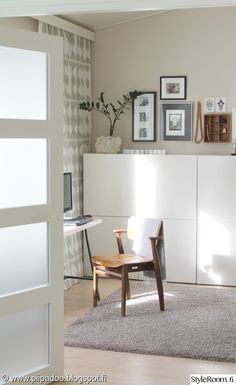 a living room filled with furniture and framed pictures on the wall above a white cabinet