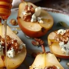 apples with walnuts and goat cheese being drizzled over them on a plate