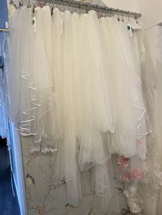 several white dresses hanging on a rack in a room