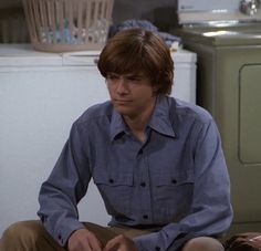 a young man sitting on the floor in front of a washer and dryer