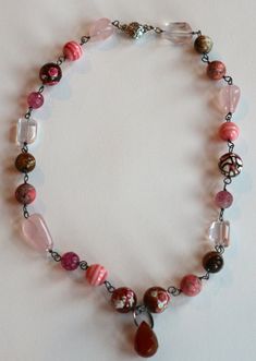 This spectacular necklace, all handmade and designed by me is made with Oxidized Sterling Silver onto which I carefully wire wrapped many stunning mirco faceted, crackled fire agate, in beautiful tones of pink, brown, blue and white.  Two types of rose quartz nuggets  provide contrast to the large 14mm fire agates.  One is faceted and angular the other nugget is smooth and soft.  In the center I hung a huge carnelian teardrop briolette bead.  This focal stone measures 18x12 mm and is a stunning Wire Wrapped Necklaces With Round Beads, Unique Wire Wrapped Necklaces With Round Beads, Unique Wire Wrapped Necklace With Round Beads, Handmade Pink Czech Glass Necklaces, Handmade Pink Czech Glass Necklace, Wire Wrapped Czech Glass Crystal Necklaces For Jewelry Making, Unique Pink Wire-wrapped Necklaces, Unique Pink Wire Wrapped Necklaces, Artisan Czech Glass Wire Wrapped Necklaces