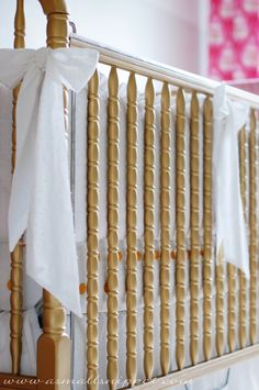 a baby crib with white and gold bedding