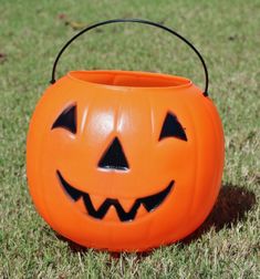 an orange halloween pumpkin bucket sitting in the grass