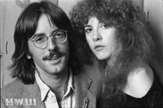 a man with long hair and glasses next to a woman